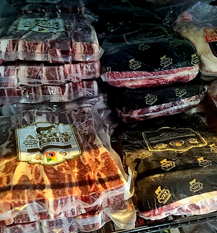 Geladeira cheia de cortes embalados a vácuo, com selos Angus Beef, VPJ e Estância 92